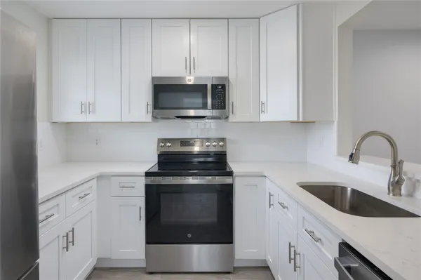 a kitchen with white cabinets and stainless steel appliances