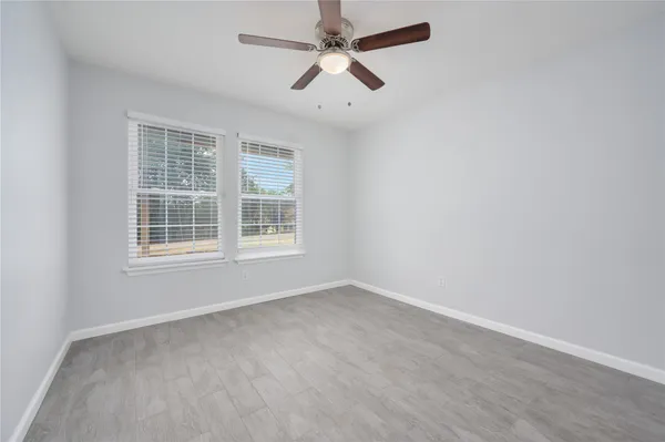 an empty room with ceiling fan and window