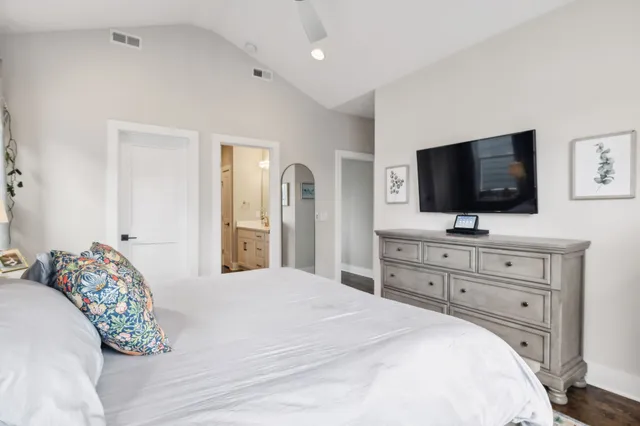 a bedroom with a bed and a flat screen tv in white dresser