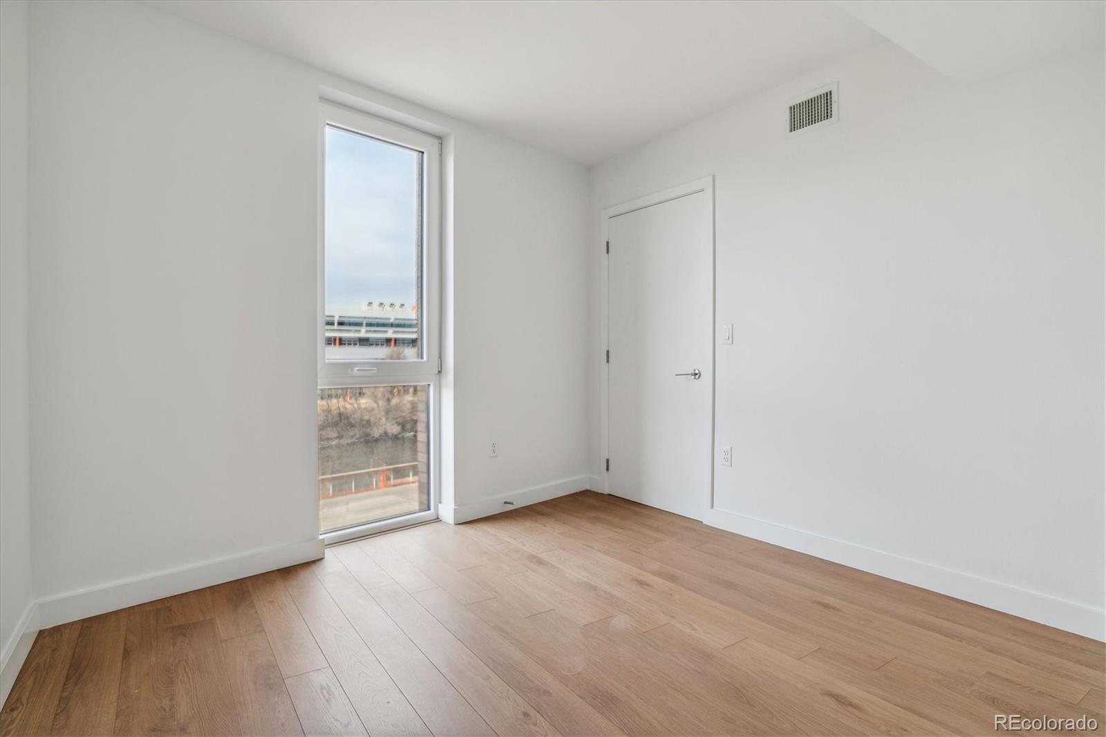 3575 Chestnut Place, Unit 402 Denver, CO 80216 - Photo 11 of 16 an empty room with wooden floor and windows