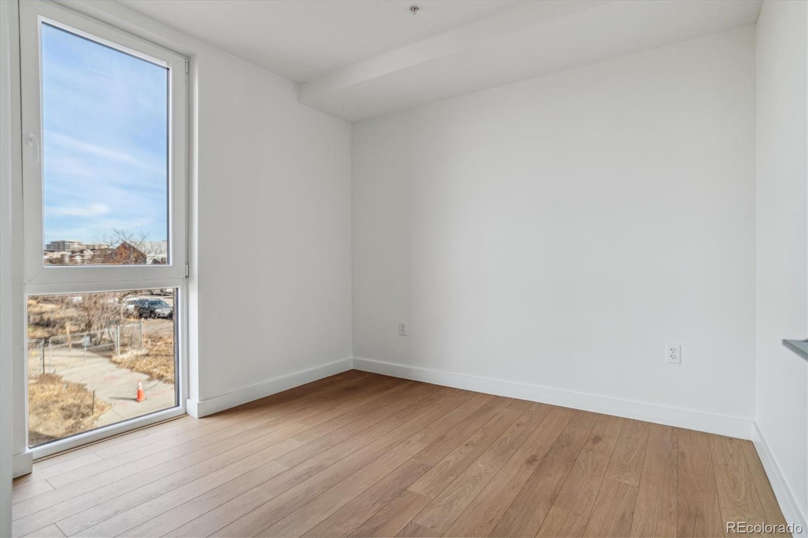 3575 Chestnut Place, Unit 402 Denver, CO 80216 - Photo 13 of 16 a view of an empty room with wooden floor and a window