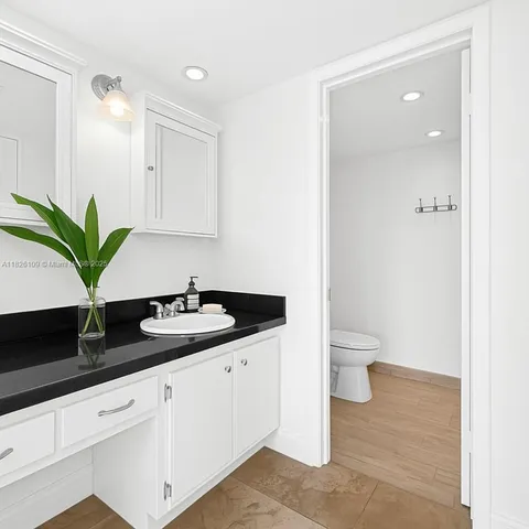 a bathroom with a granite countertop sink a toilet and a mirror