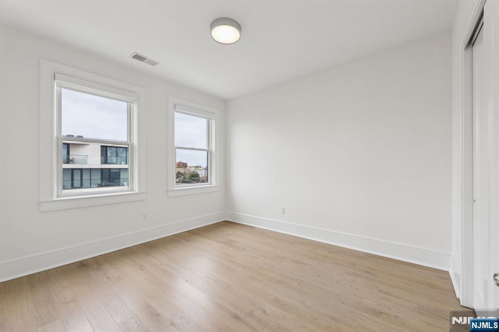 209-211 Hackensack Plank Road, Unit 5B Weehawken, NJ 07086 - Photo 23 of 30 an empty room with wooden floor and windows