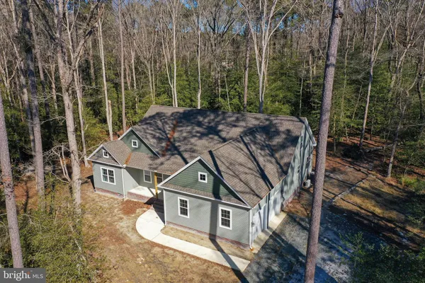 an empty room with wooden floor a fireplace a ceiling fan and windows