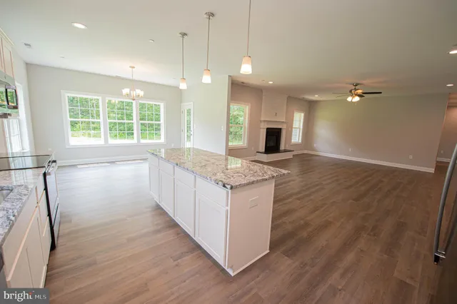 a open kitchen with granite countertop a stove top oven a sink dishwasher and a fireplace with wooden floor