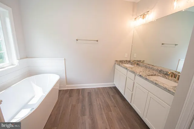 a bathroom with a granite countertop sink a vanity and bathtub