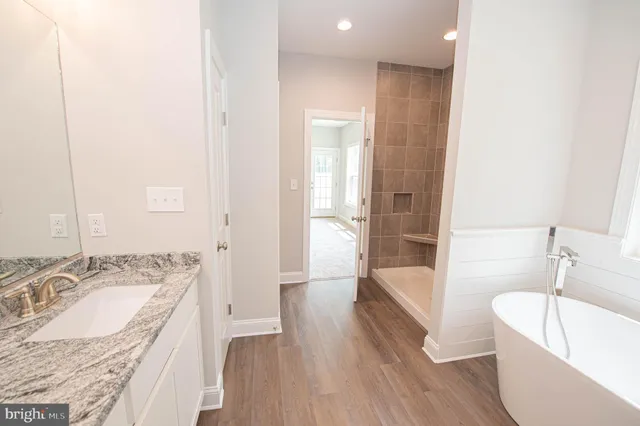 a bathroom with a granite countertop tub sink and mirror
