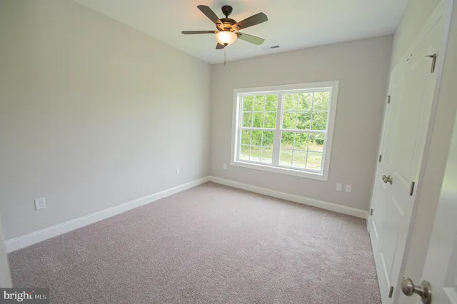 an empty room with a window and a fan