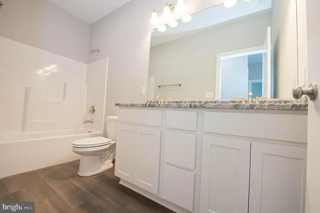a bathroom with a granite countertop toilet sink and mirror