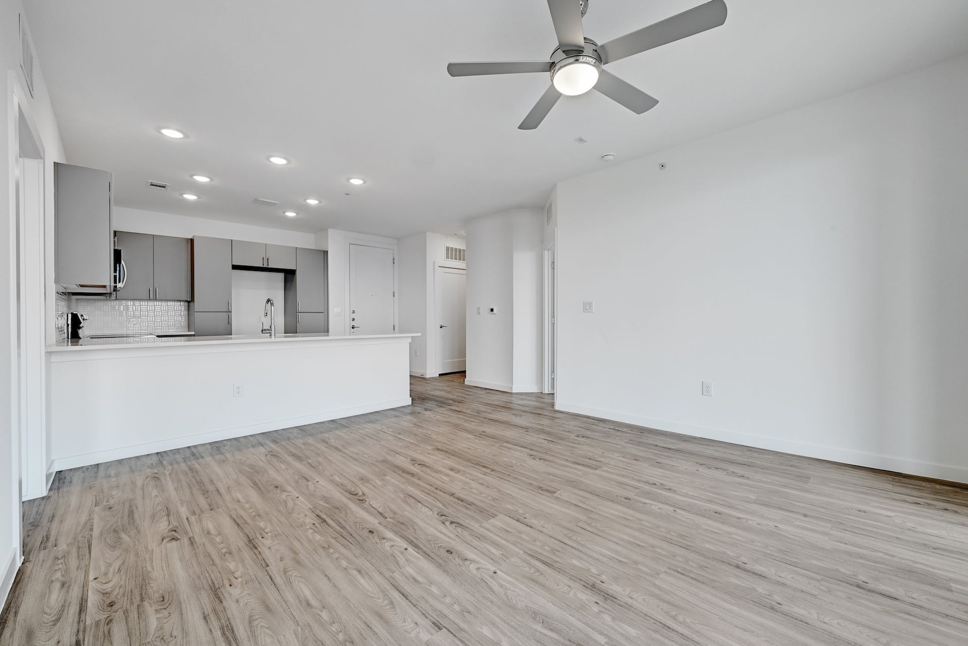 4801 Springdale Road, Unit 1301 Austin, TX 78723 - Photo 10 of 39 A streamlined open-concept kitchen flows seamlessly into the living area, featuring light wood flooring and overhead lighting.