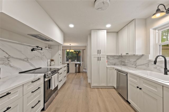 a kitchen with white cabinets and sink