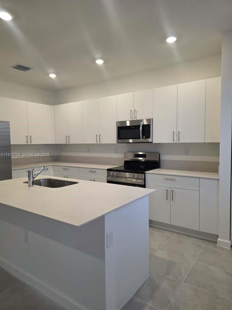 17875 Southwest 359 Terrace Homestead, FL 33034 - Photo 6 of 20 a kitchen with kitchen island white cabinets appliances and a sink