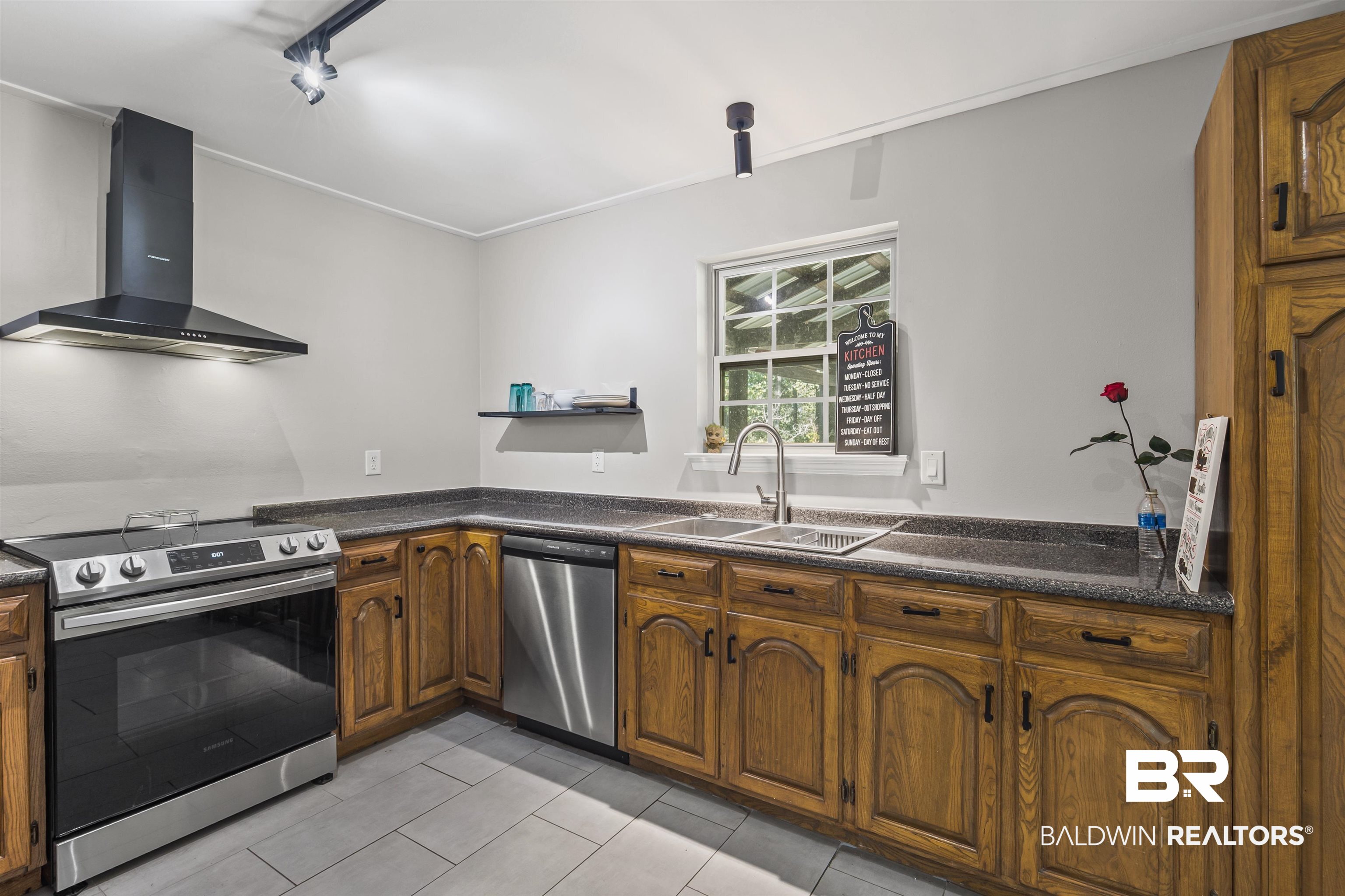 8911 Owassa Road Evergreen, AL 36401 - Photo 4 of 24 Kitchen featuring appliances with stainless steel finishes, wall chimney range hood, brown cabinets, light tile patterned floors, and open shelves
