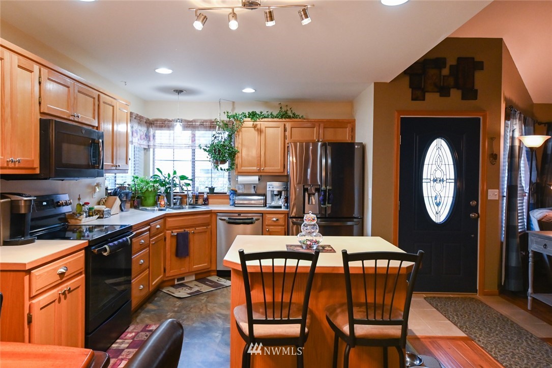 1018 Gohr Road Sultan, WA 98294 - Photo 5 of 16 a kitchen with stainless steel appliances granite countertop a refrigerator a stove a sink a dining table and chairs with wooden floor