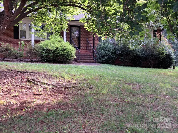 a view of a backyard with potted plants and large trees