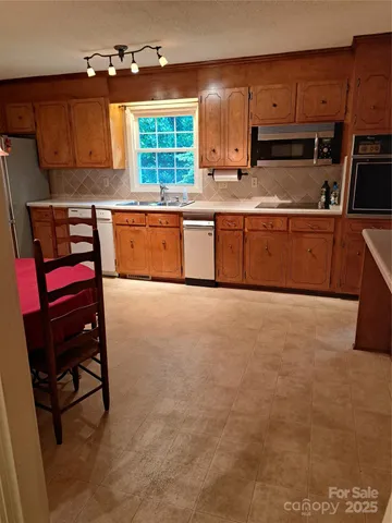 a kitchen with stainless steel appliances a sink a stove a refrigerator cabinets and a window