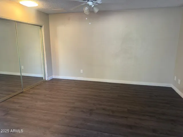 an empty room with wooden floor and fan