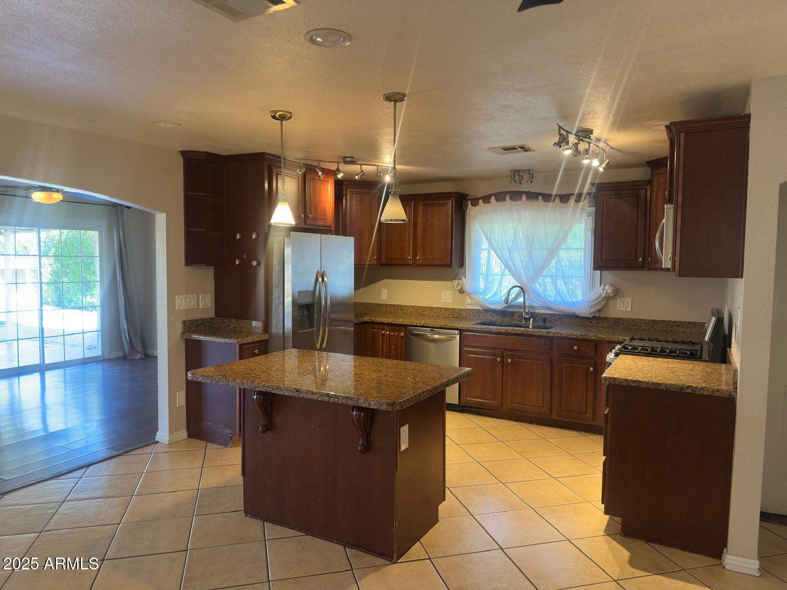 7728 North 47th Drive Glendale, AZ 85301 - Photo 16 of 23 a kitchen with granite countertop a sink counter top space cabinets and stainless steel appliances