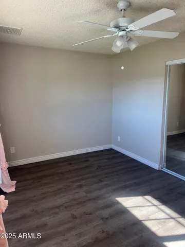 an empty room with wooden floor and fan