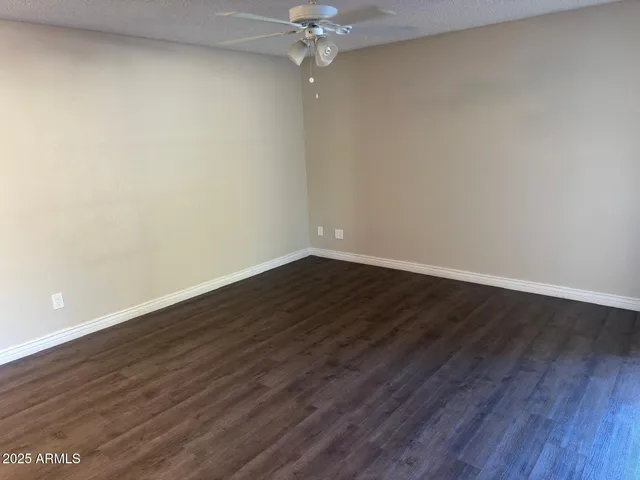 a view of a room with wooden floor and a ceiling fan
