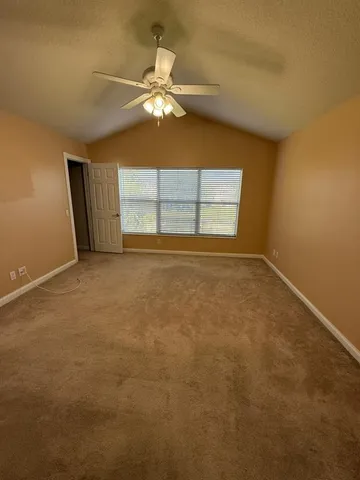 an empty room with a chandelier fan and windows