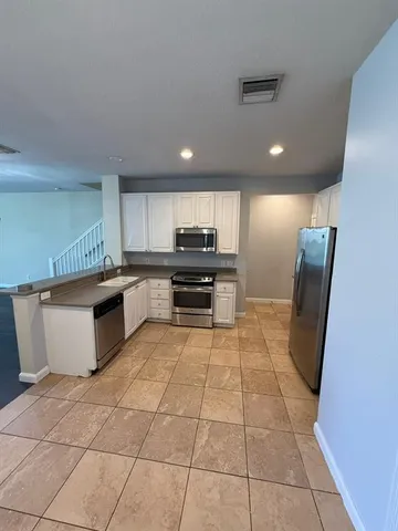a kitchen with granite countertop a refrigerator and a stove top oven