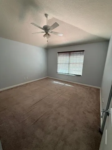 an empty room with windows and fan