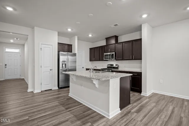 a kitchen with stainless steel appliances granite countertop a refrigerator stove a sink and a oven with wooden floor