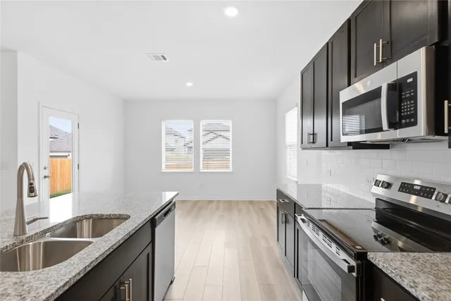 a kitchen with stainless steel appliances granite countertop a sink stove and microwave