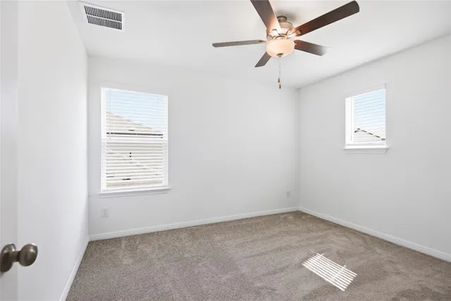 an empty room with a window and a ceiling fan