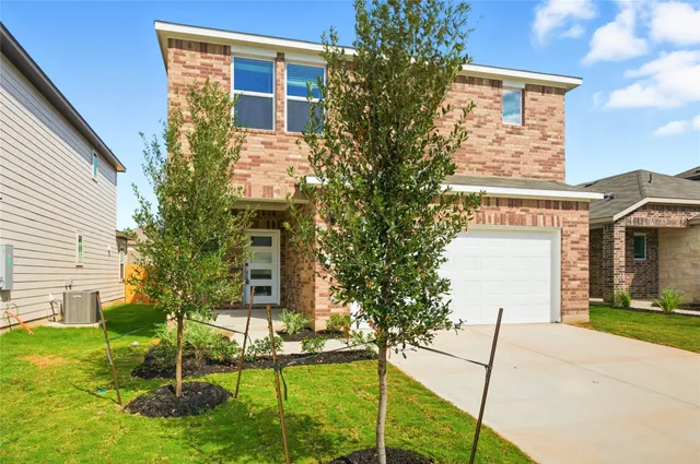 a view of a brick house with a yard and plants