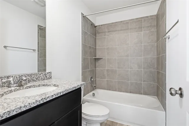 a bathroom with a granite countertop bathtub shower sink vanity and toilet