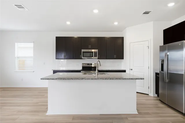 a large kitchen with stainless steel appliances granite countertop a stove a sink and a microwave