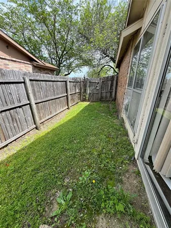 a view of backyard with green space and wooden fence