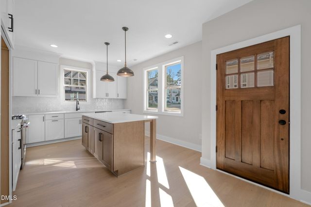 a large kitchen with stainless steel appliances granite countertop a stove a sink and a refrigerator with wooden floors