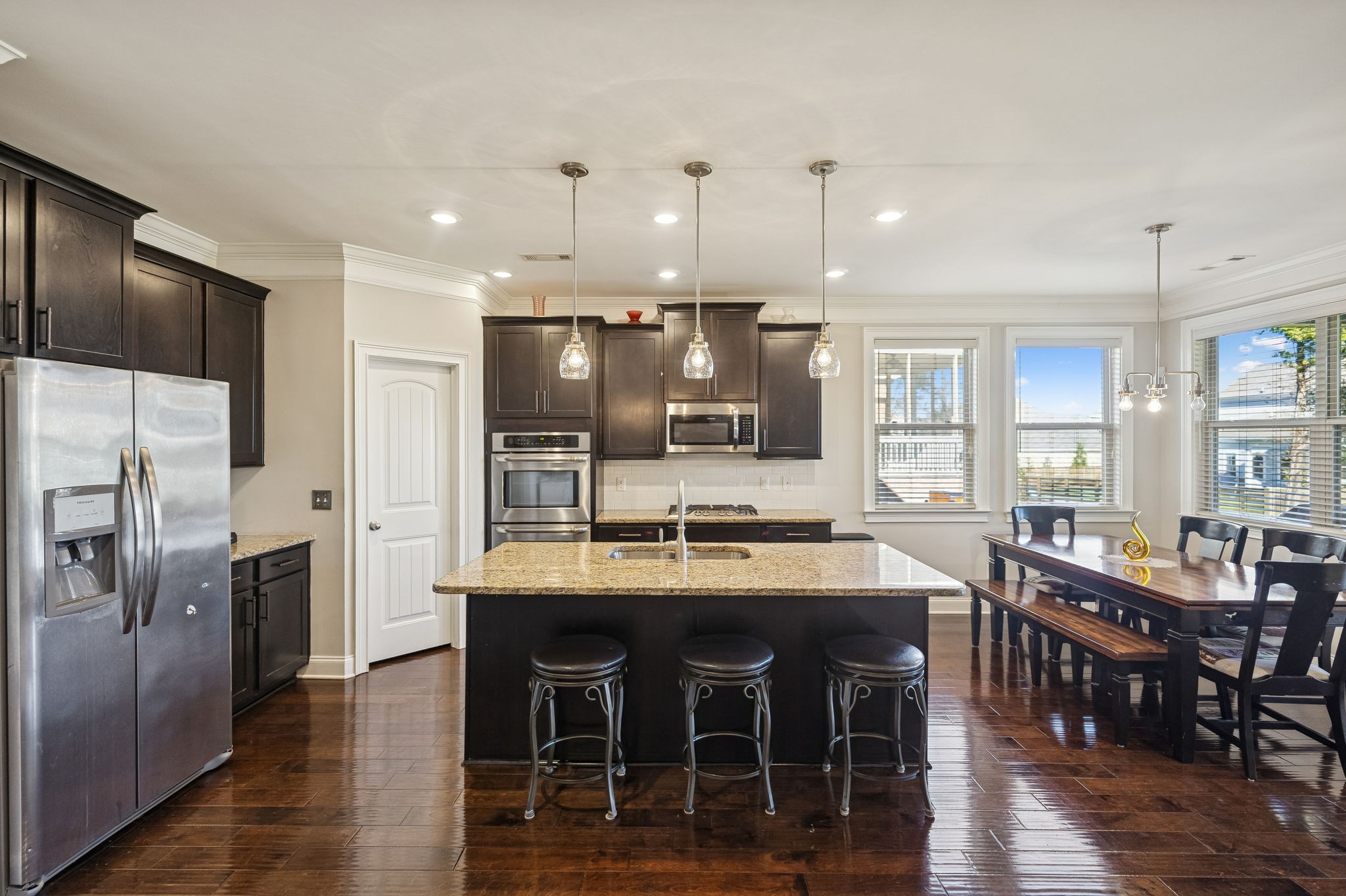 1167 Batbriar Road Murfreesboro, TN 37128 - Photo 6 of 22 a kitchen with stainless steel appliances kitchen island granite countertop a dining table chairs and wooden floor