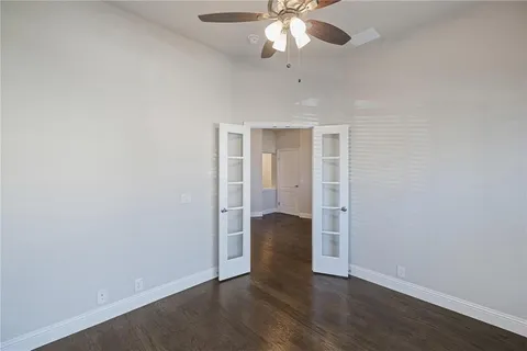 an empty room with wooden floor and chandelier fan