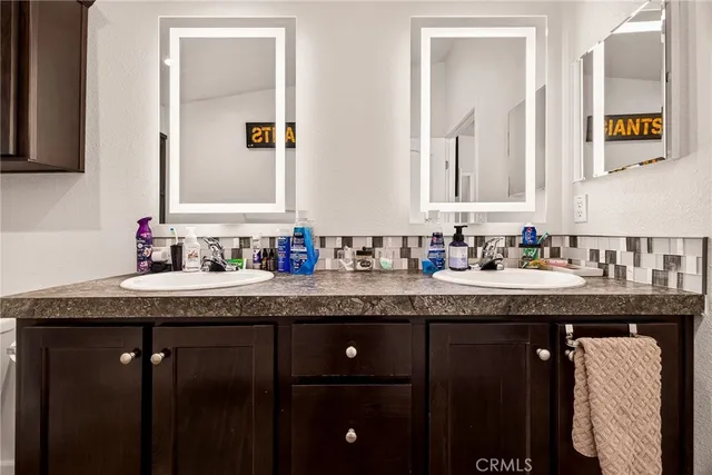 a bathroom with a granite countertop double vanity and a mirror