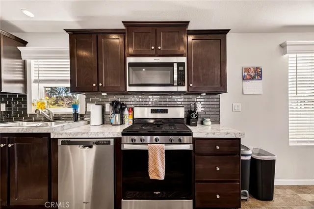 a kitchen with granite countertop a sink stove and microwave