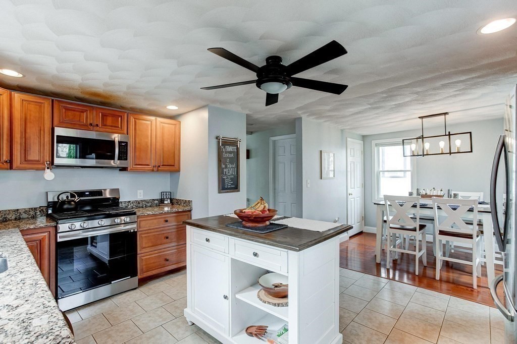 54 Pine Street Stoneham, MA 02180 - Photo 12 of 30 a kitchen with stainless steel appliances kitchen island granite countertop a stove top oven a sink a dining table and chairs