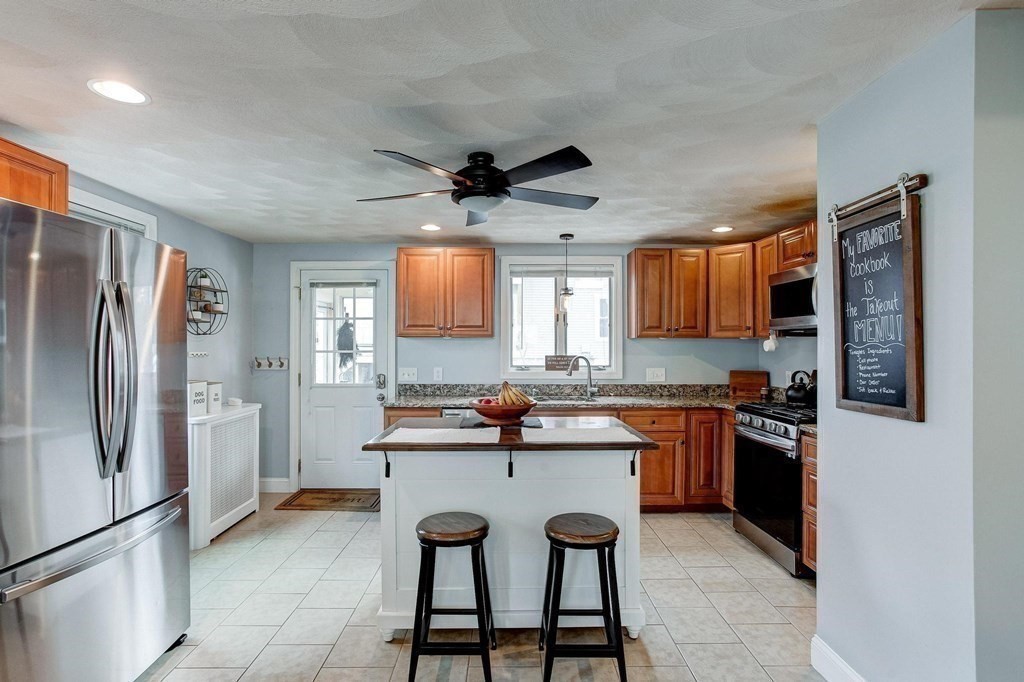 54 Pine Street Stoneham, MA 02180 - Photo 9 of 30 a kitchen with stainless steel appliances granite countertop a refrigerator a sink a stove a dining table and chairs