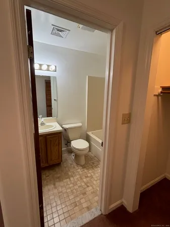 a bathroom with a granite countertop toilet sink and mirror