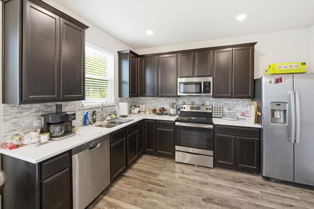 10701 Kestrel Court Waco, TX 76708 - Photo 2 of 37 Kitchen with stainless steel appliances, dark wood finish cabinetry, light wood-look flooring, and recessed LED lighting