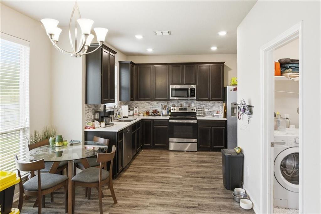 10701 Kestrel Court Waco, TX 76708 - Photo 5 of 37 Kitchen with stainless steel appliances, dark wood finish cabinets, decorative and LED lighting, light wood-look floors, and laundry room to the side