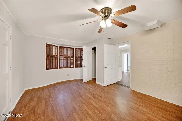 a view of an empty room with window and wooden floor