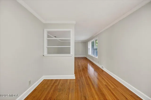 a view of an empty room with wooden floor and windows