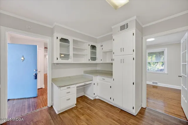 a kitchen with white cabinets and wooden floor