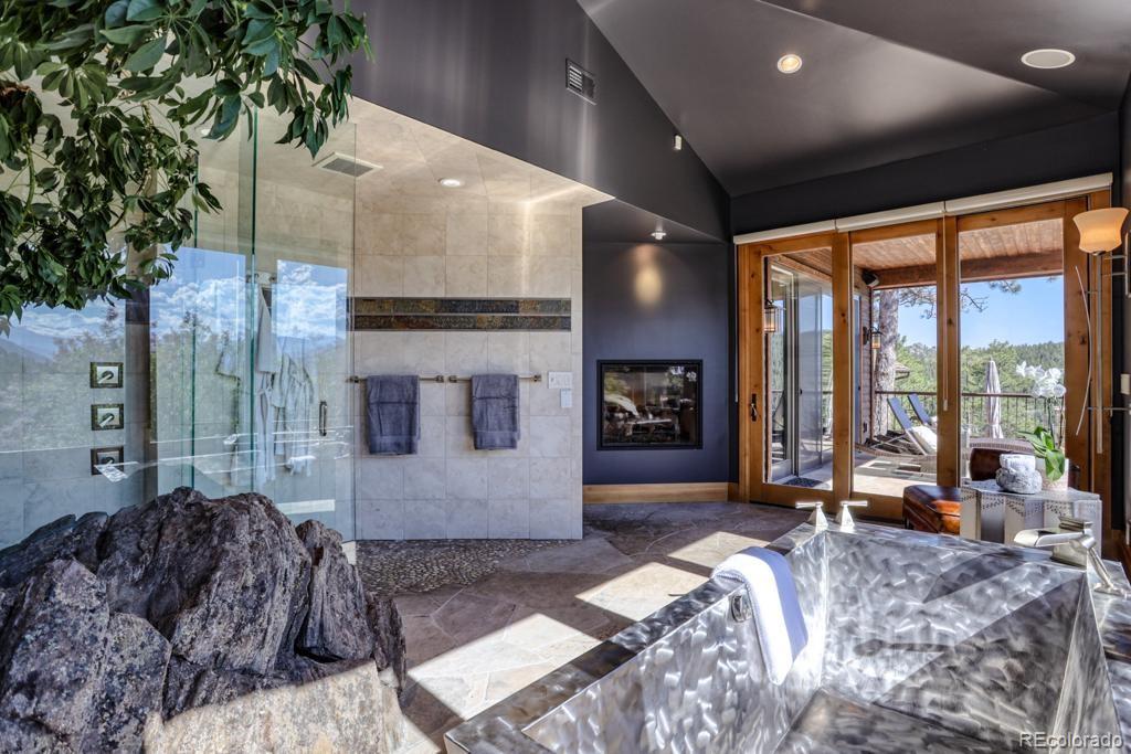 3731 Overlook Trail Evergreen, CO 80439 - Photo 13 of 35 a spacious bedroom with a large window and a chandelier