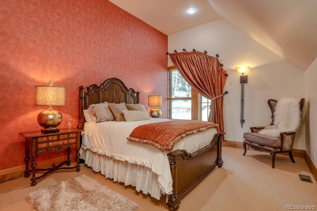 3731 Overlook Trail Evergreen, CO 80439 - Photo 24 of 35 a spacious bedroom with a bed and a chandelier