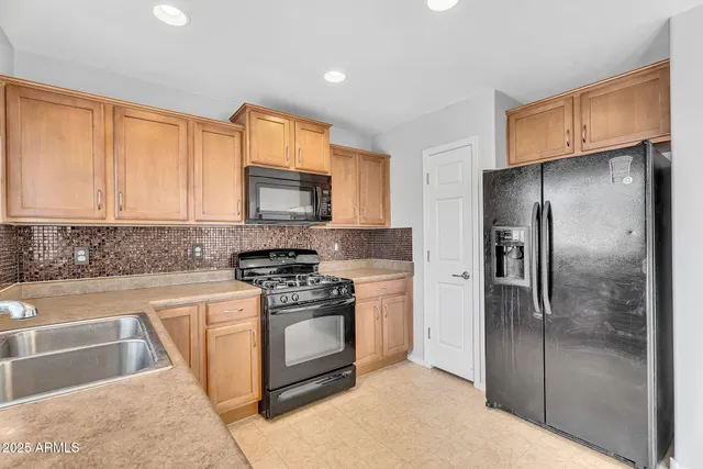 a kitchen with stainless steel appliances granite countertop a refrigerator a stove a sink and a microwave